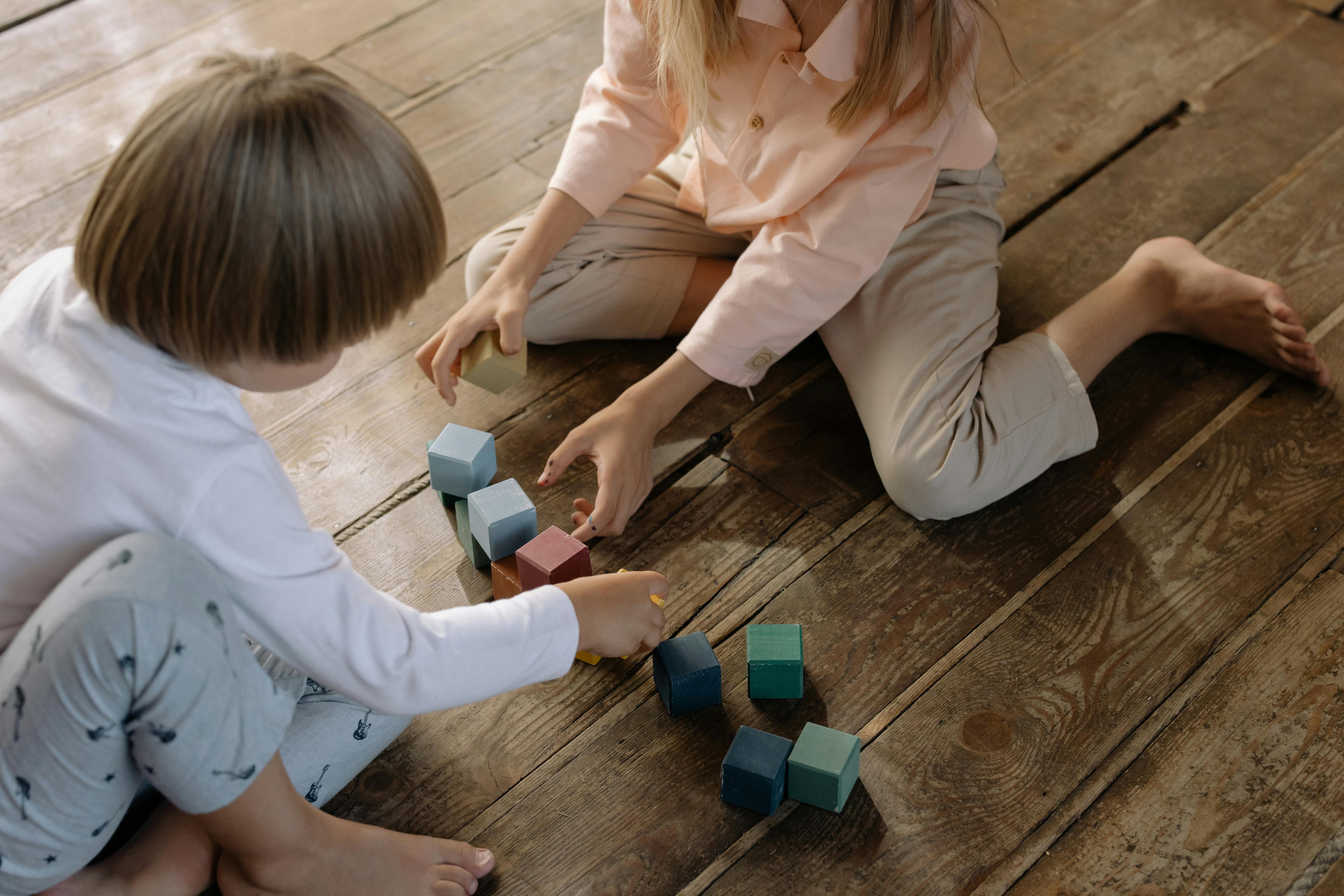 Kind und Erzieherin spielen gemeinsam auf dem Boden