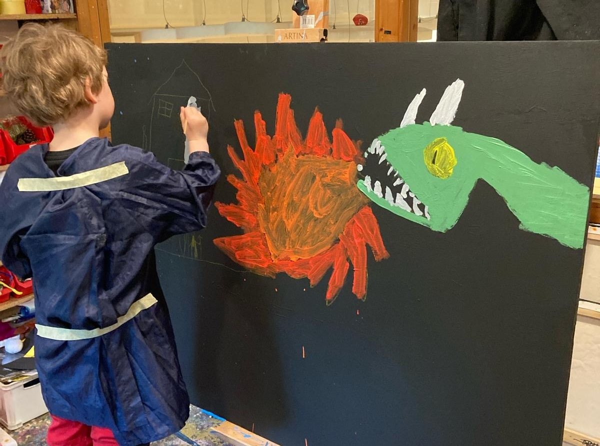 A child painting a big dragon on a black canvas