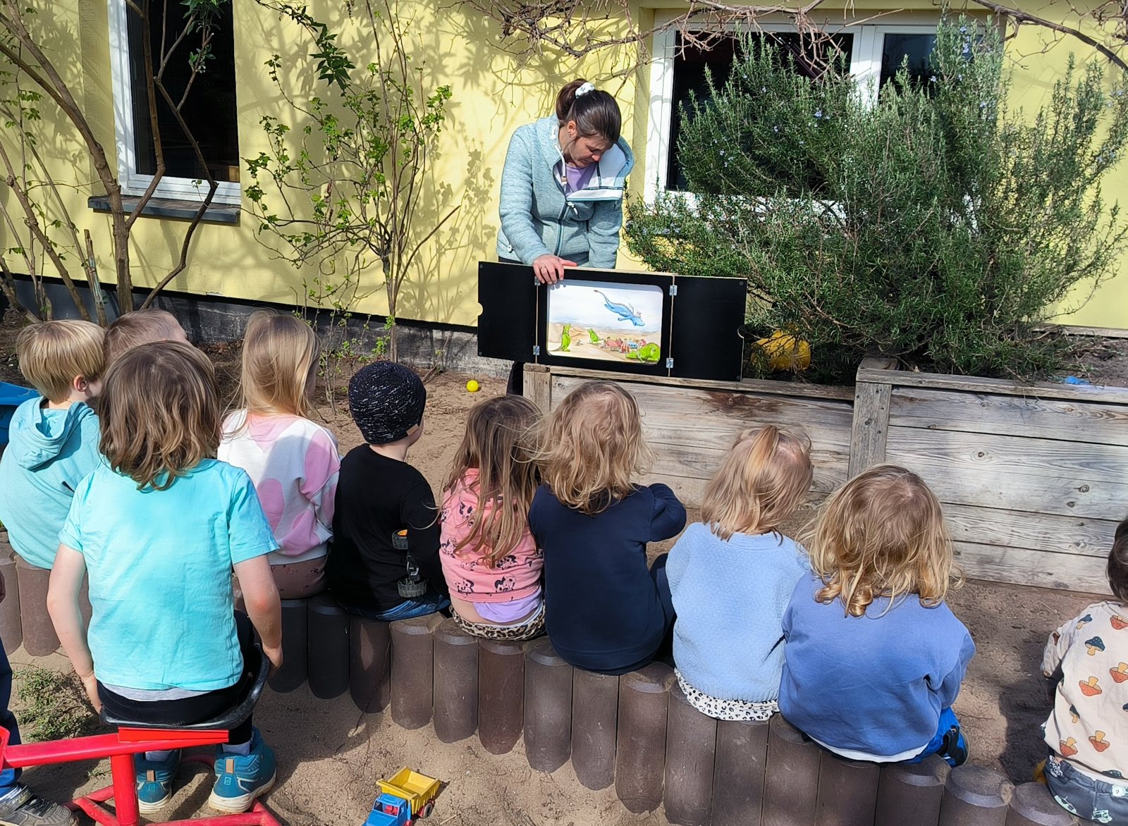 Children listening to a kamishibai story in the garden