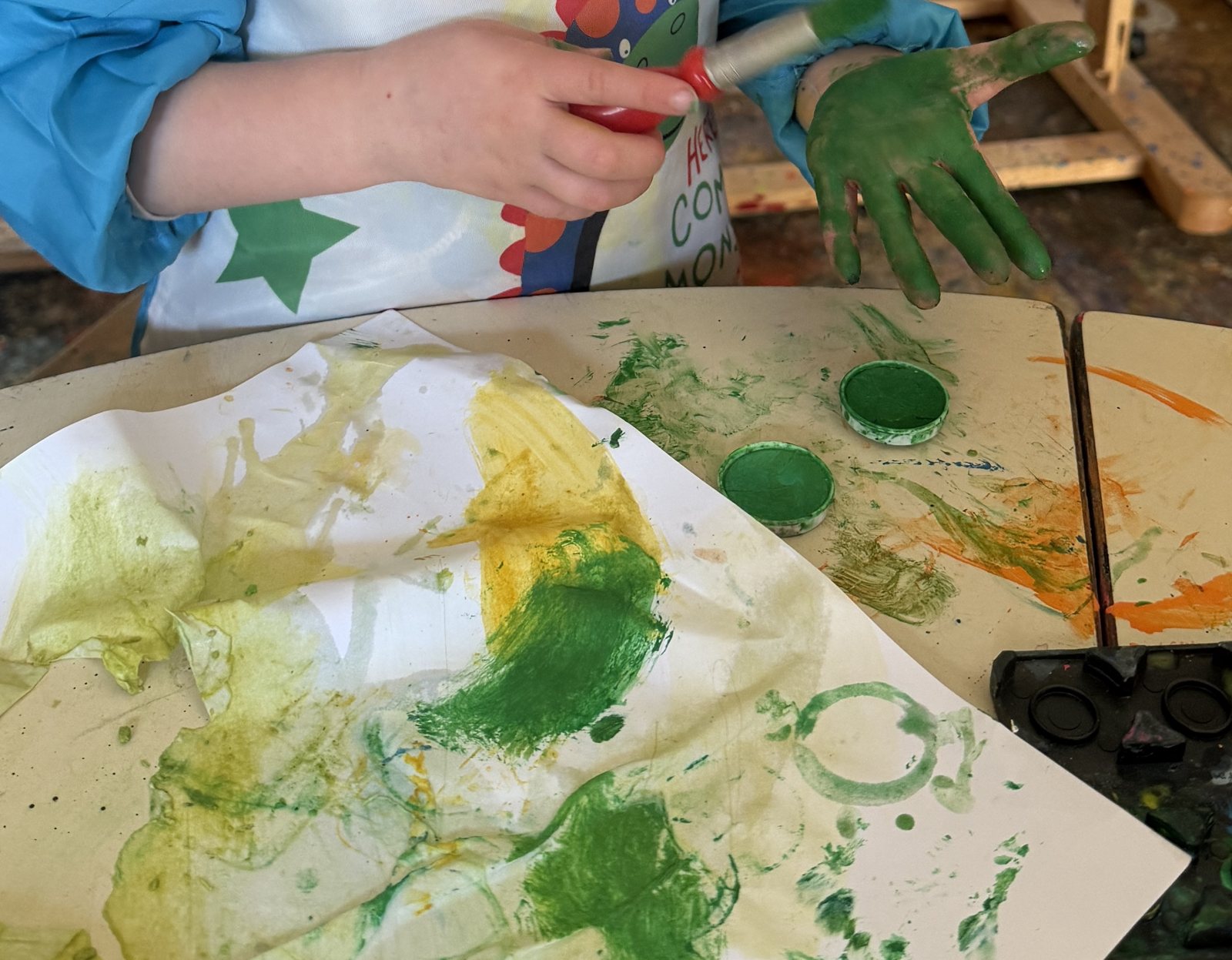 Children's hands painting with green paint