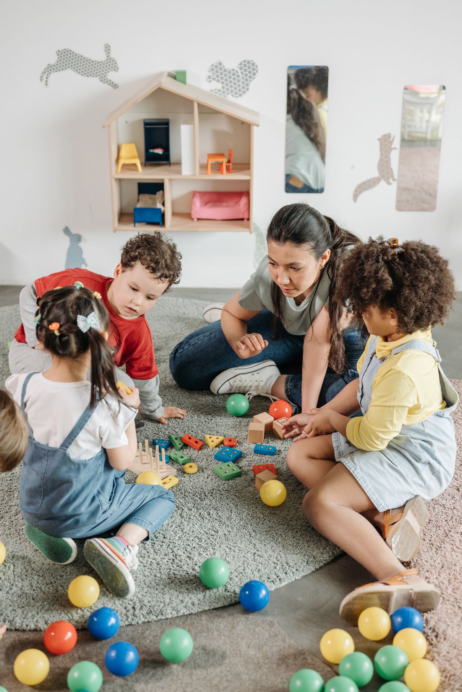 Kinder spielen gemeinsam mit einer Erzieherin