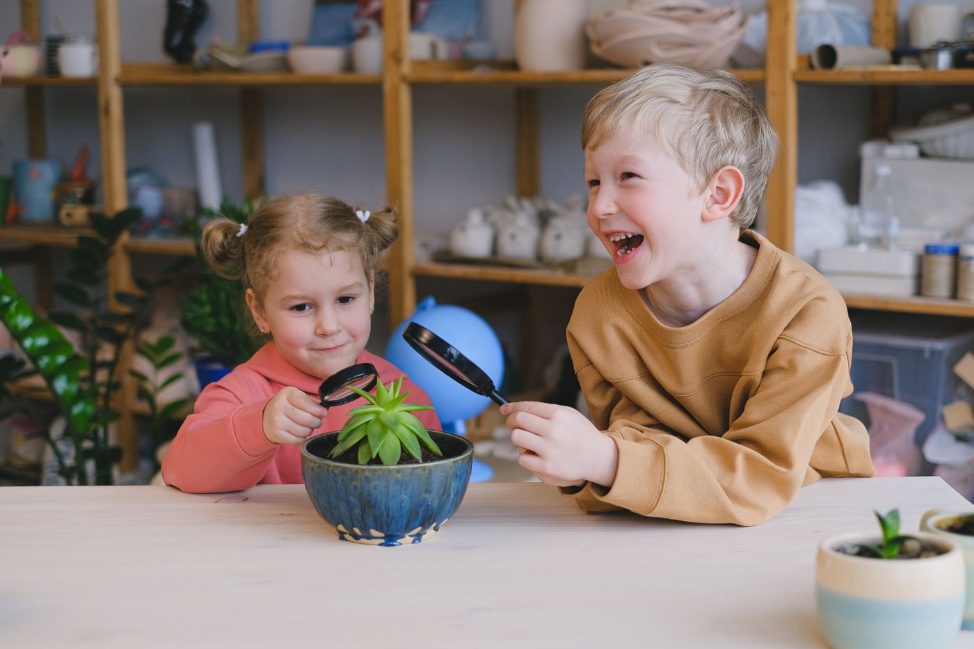 Zwei Kinder entdecken eine Pflanze mit der Lupe